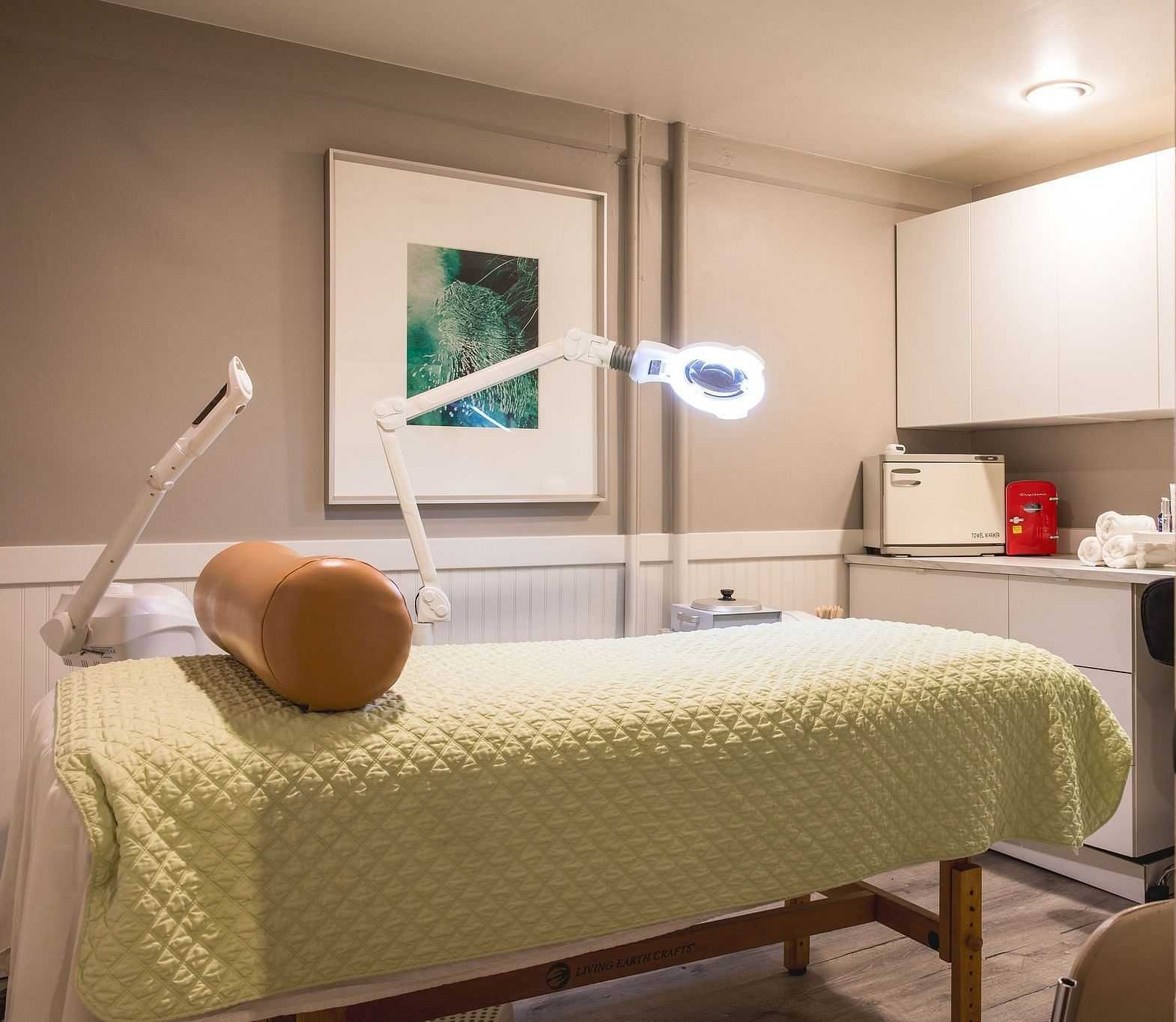 Medical treatment room with a treatment table, specialized lighting, and medical equipment.