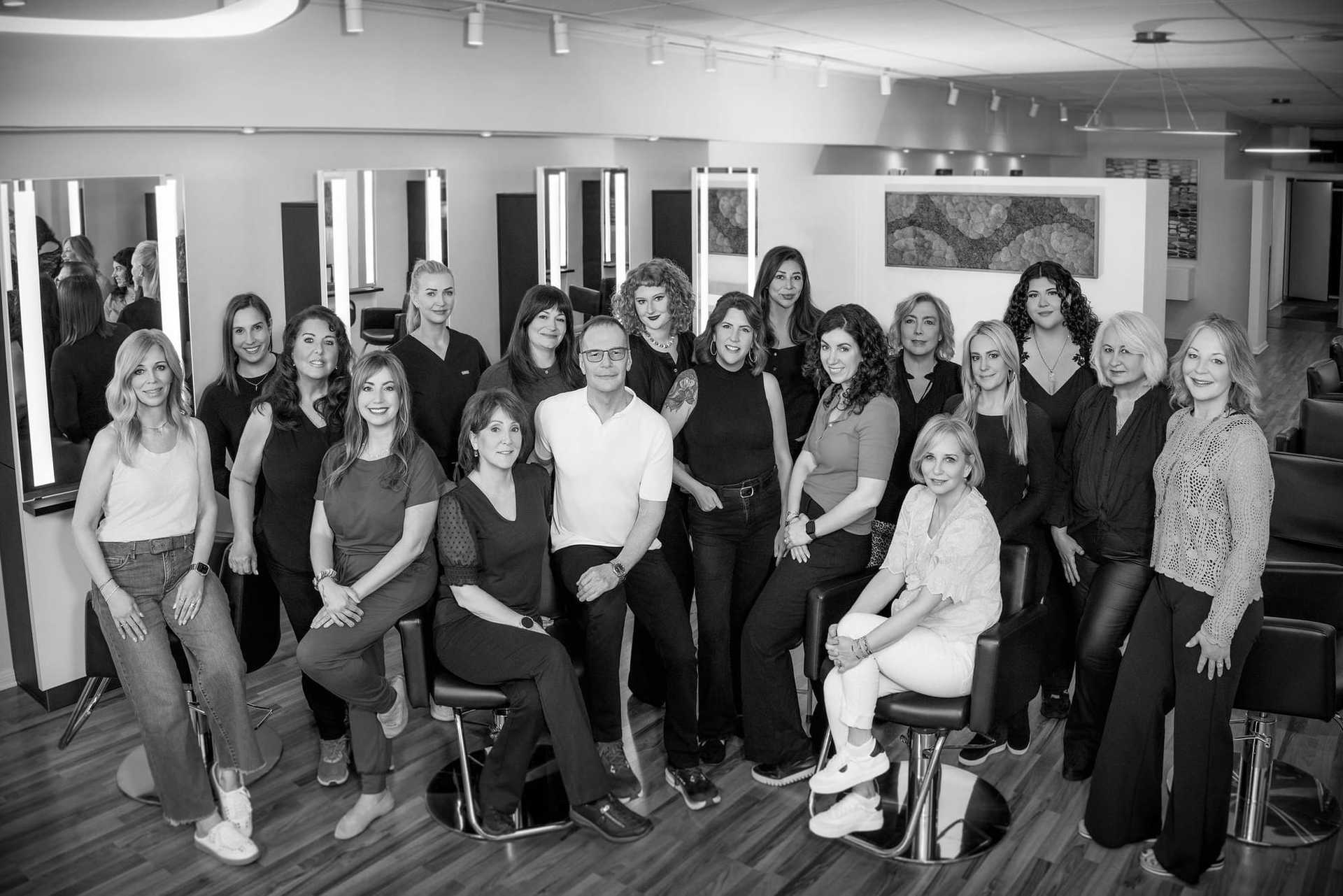 Group of salon staff posing together inside a modern, well-lit hair salon.